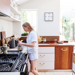 Woman Wearing Pajamas At Home In Kitchen Making Fresh Coffee